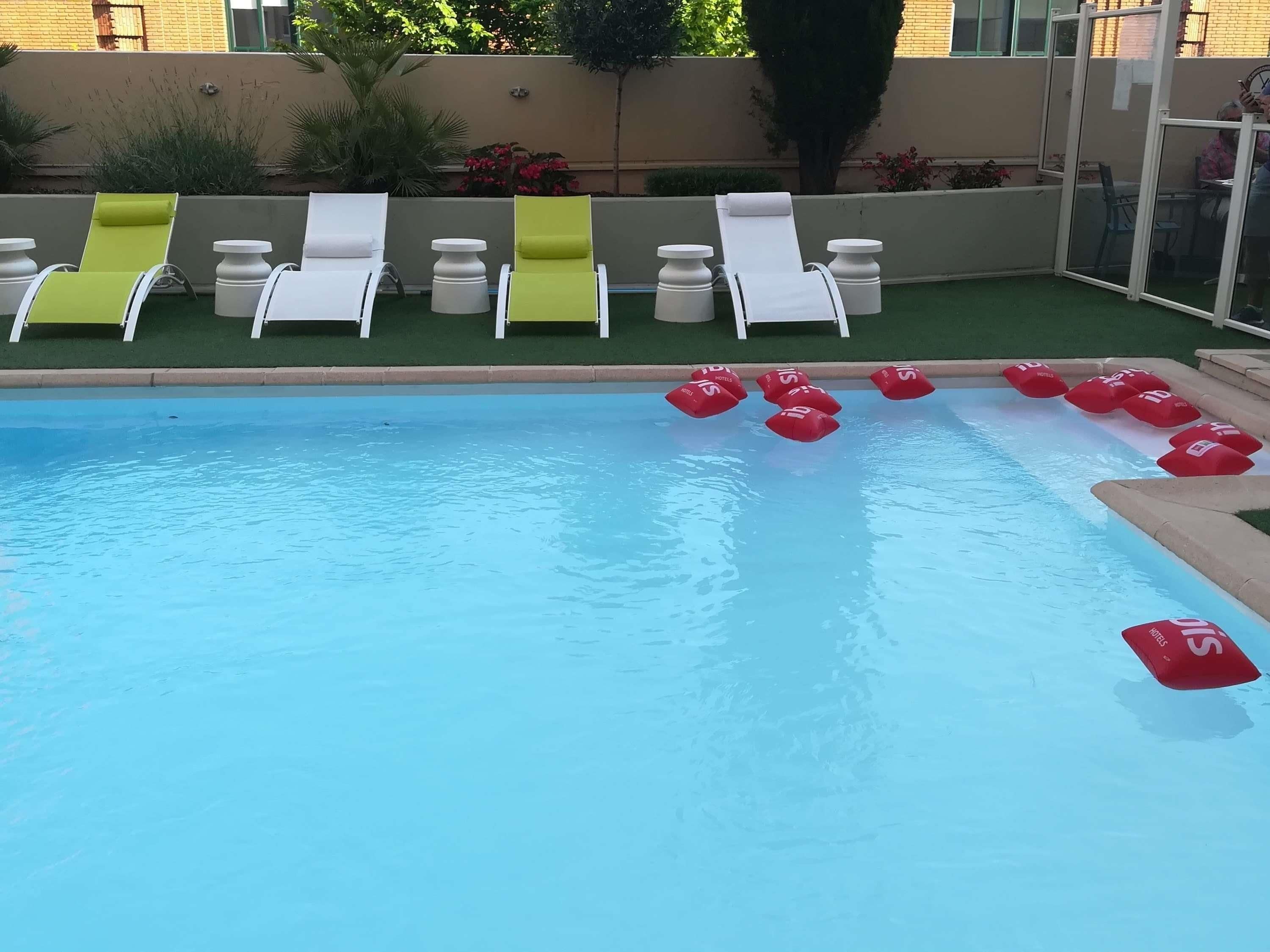 Una piscina con sillas de descanso y boyas rojas.