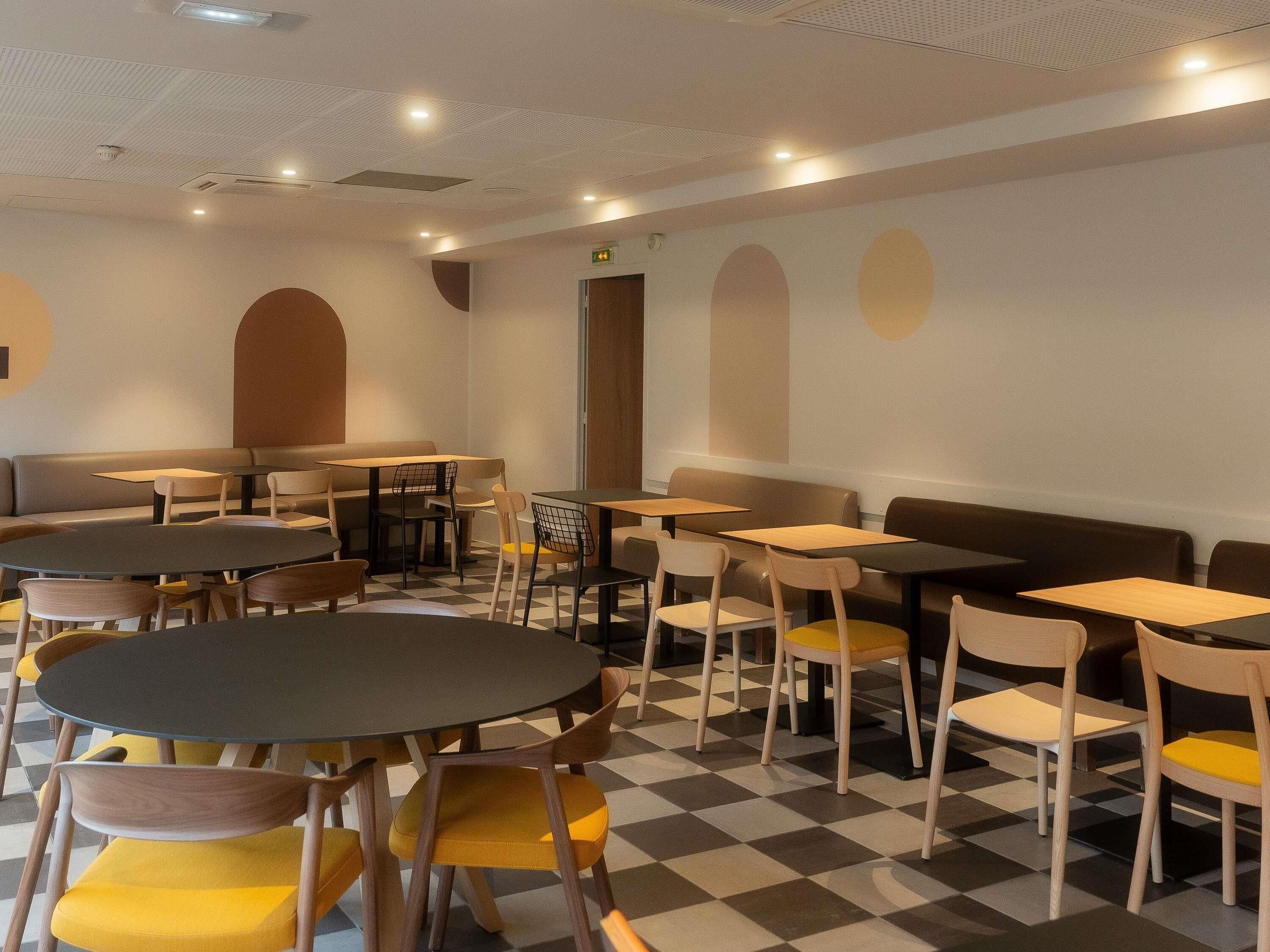 A cafe with round tables and chairs, a checkered floor, and a simple, modern design.