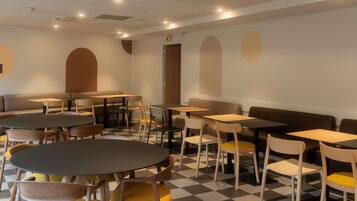 Una cafetería con mesas y sillas redondas, piso a cuadros y un diseño sencillo y moderno.