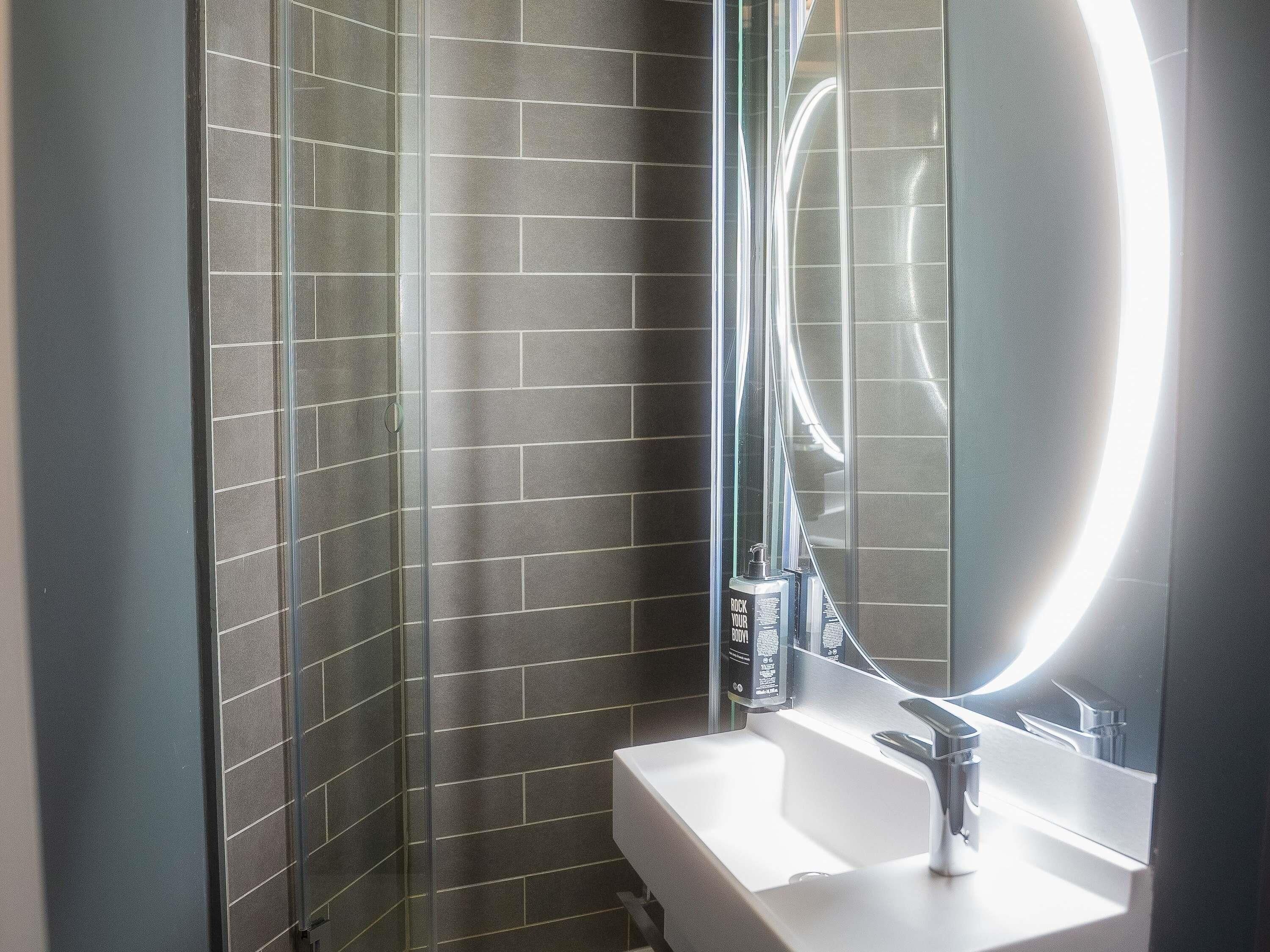 Un baño con ducha, lavabo y espejo.