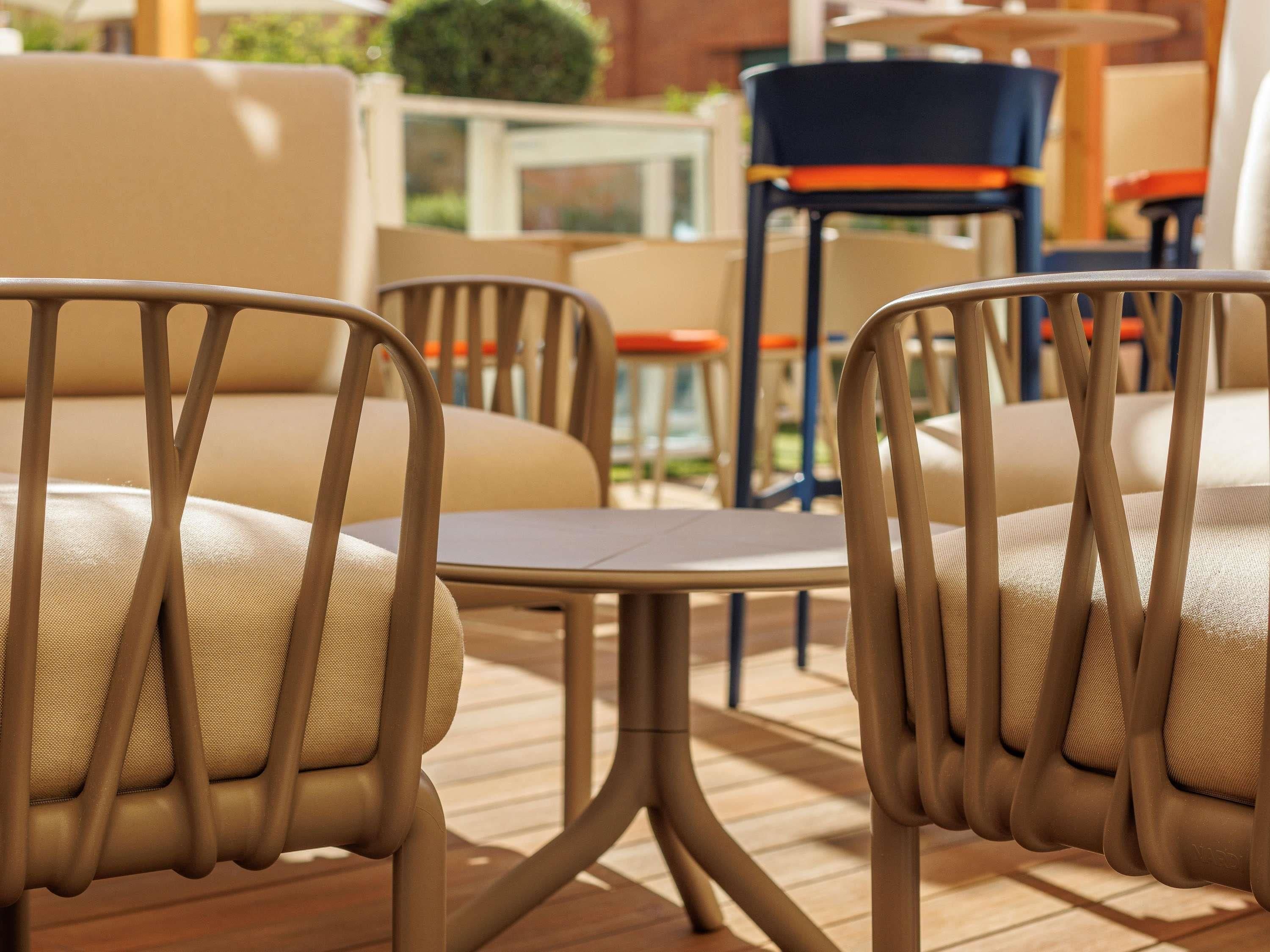 Een zithoek met stoelen en tafels, een klein tafeltje en een stoel met kussen.
