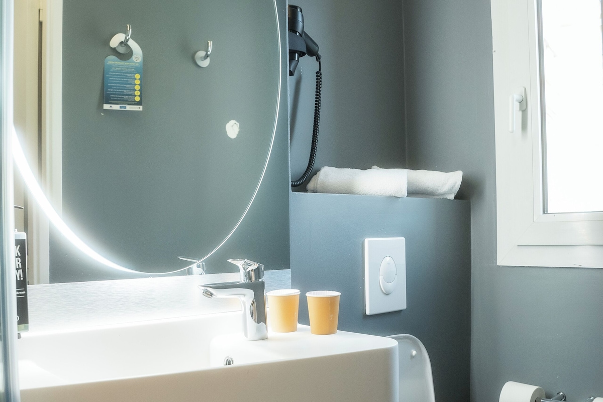 A bathroom with a white sink, a mirror, a toilet, and a towel rack.