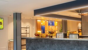 Un vestíbulo de hotel moderno con una recepción, zona de estar y un bar.