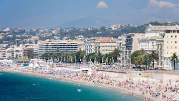 Un paisaje urbano costero con una playa concurrida, edificios y una montaña al fondo.