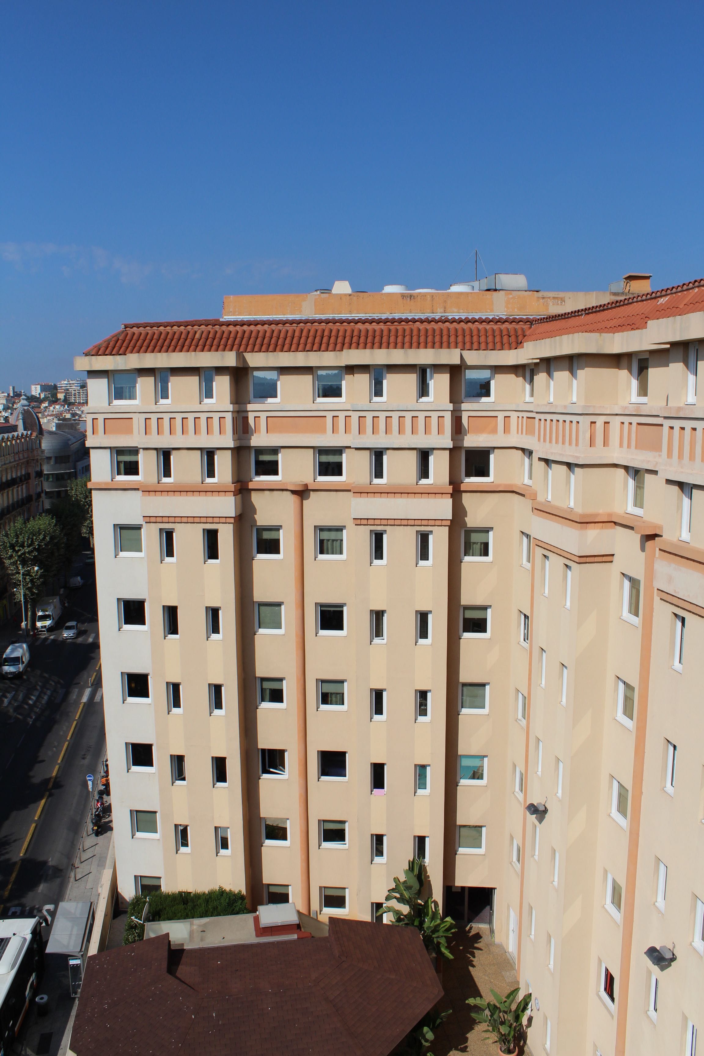 A multi-story building with a beige facade and red-tiled roof.