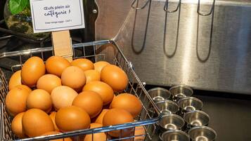 A metal basket filled with eggs, a stainless steel sink, and metal bowls.