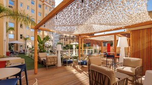A covered outdoor seating area with wooden flooring, lounge chairs, and tables. - ibis Nice Centre Gare (Nice)