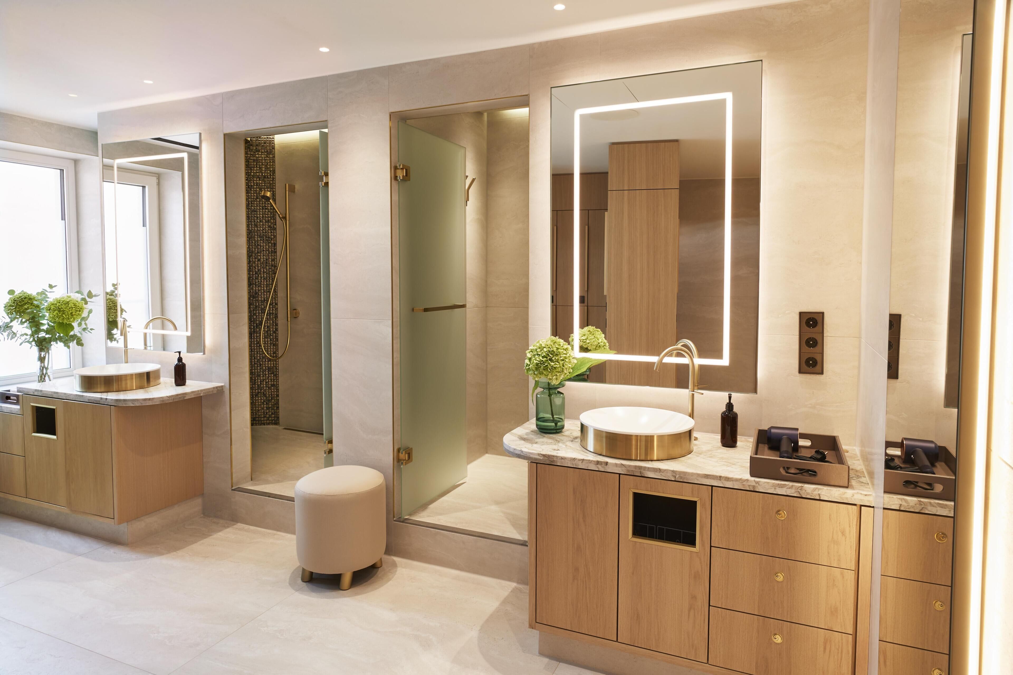 A modern bathroom with a large mirror, a round sink, and a walk-in shower.