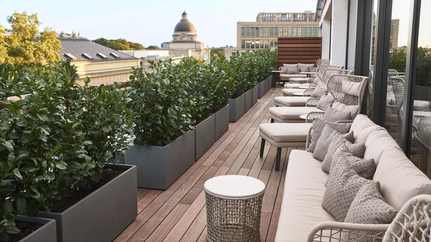 Eine Dachterrasse mit einer Couch, Stühlen und Topfpflanzen.
