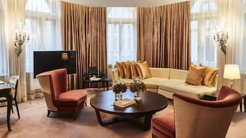 A modern living room with a sofa, two armchairs, a coffee table, and a TV.