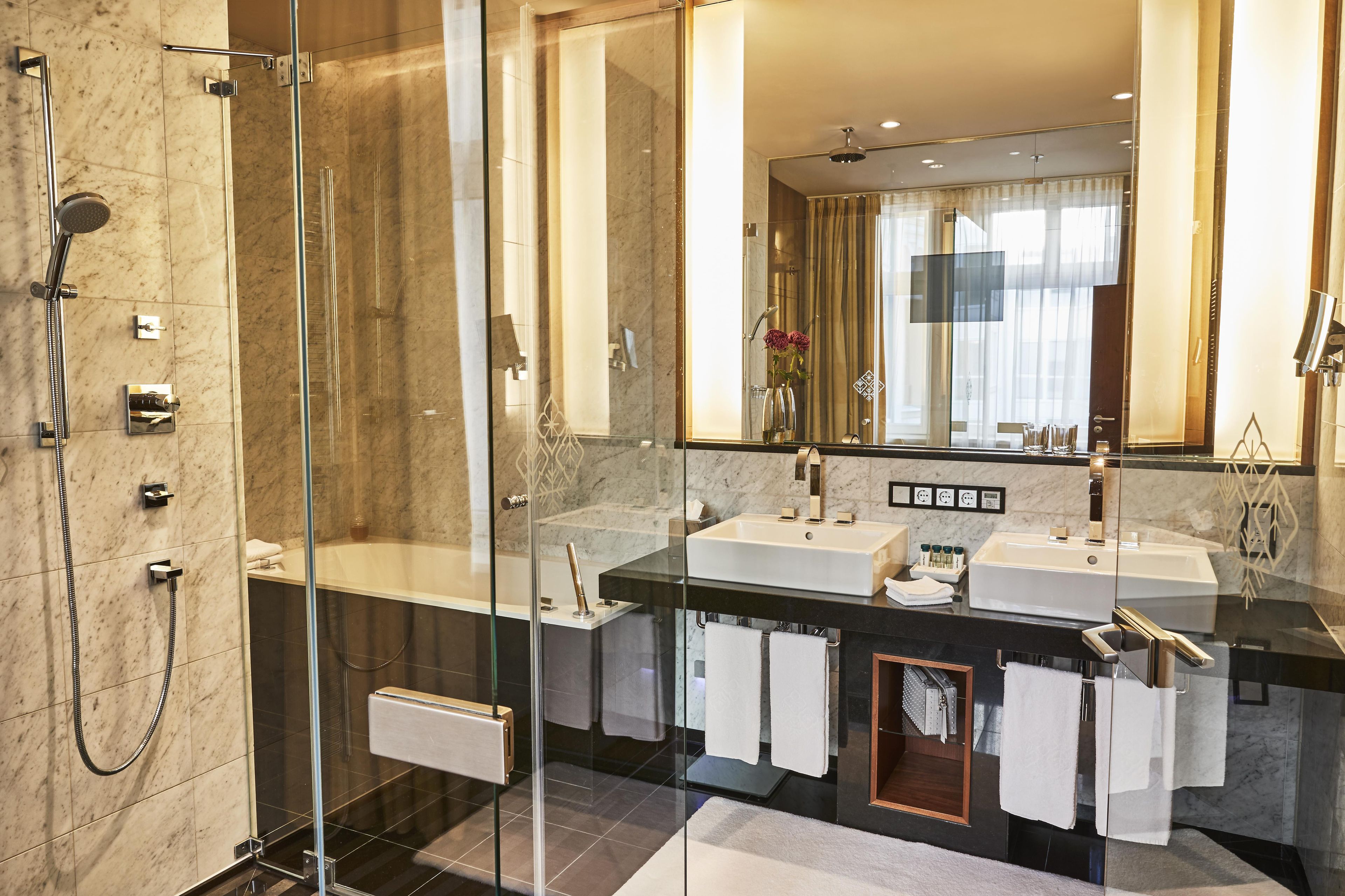 Ein modernes Badezimmer mit einer Duschkabine, zwei Waschbecken und einem großen Spiegel.