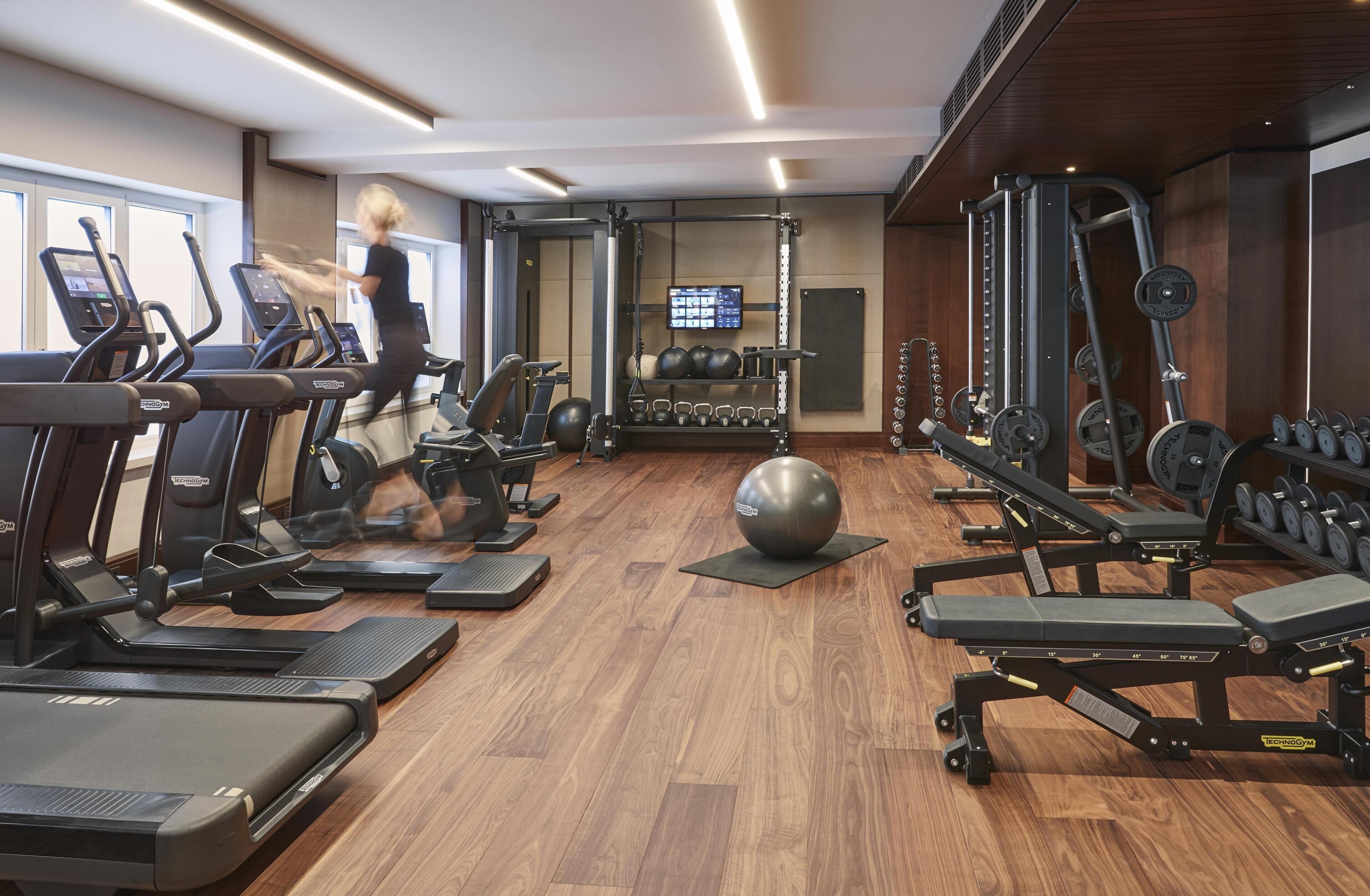 A gym with treadmills, weight machines, and a large exercise ball.