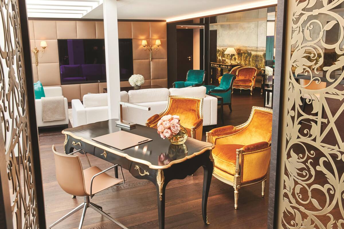 Un hall d’hôtel moderne avec un espace salon, une table agrémentée d’un vase de fleurs et une vue à travers un mur de verre.