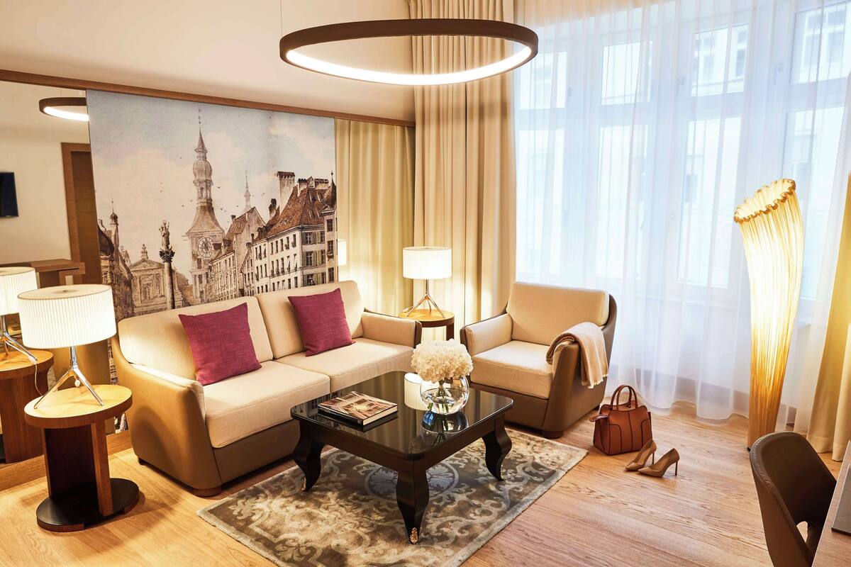 Un salon moderne avec un canapé, une table basse et des lampes. Un grand tableau représentant un paysage urbain est accroché au mur.