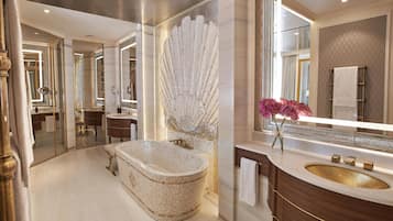 A luxurious bathroom with a large bathtub, a vanity with a gold sink, and a decorative shell wall piece.