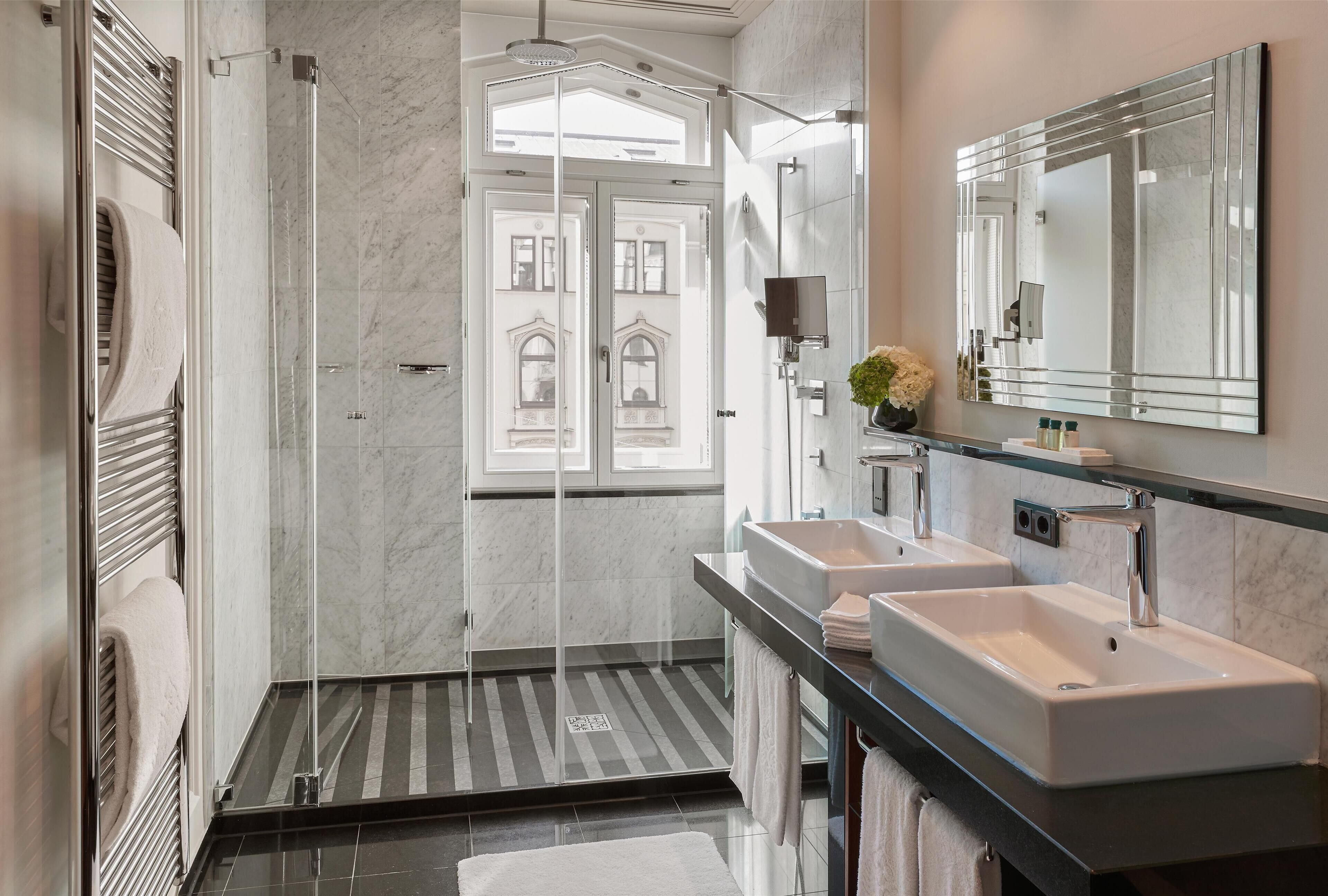 A modern bathroom with a glass-enclosed shower, two sinks, and a large mirror.