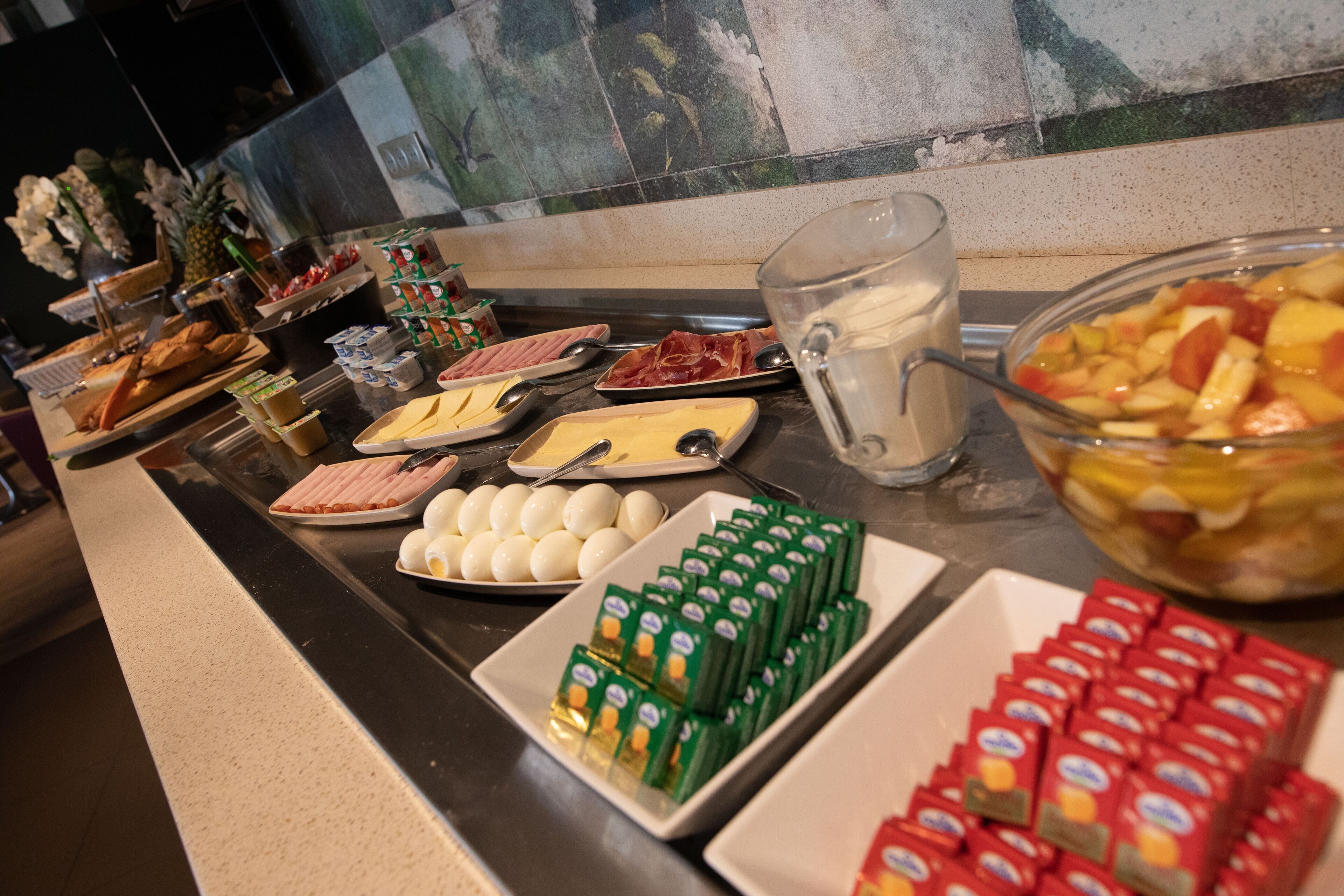 A buffet with various food items including eggs, meats, and fruits.