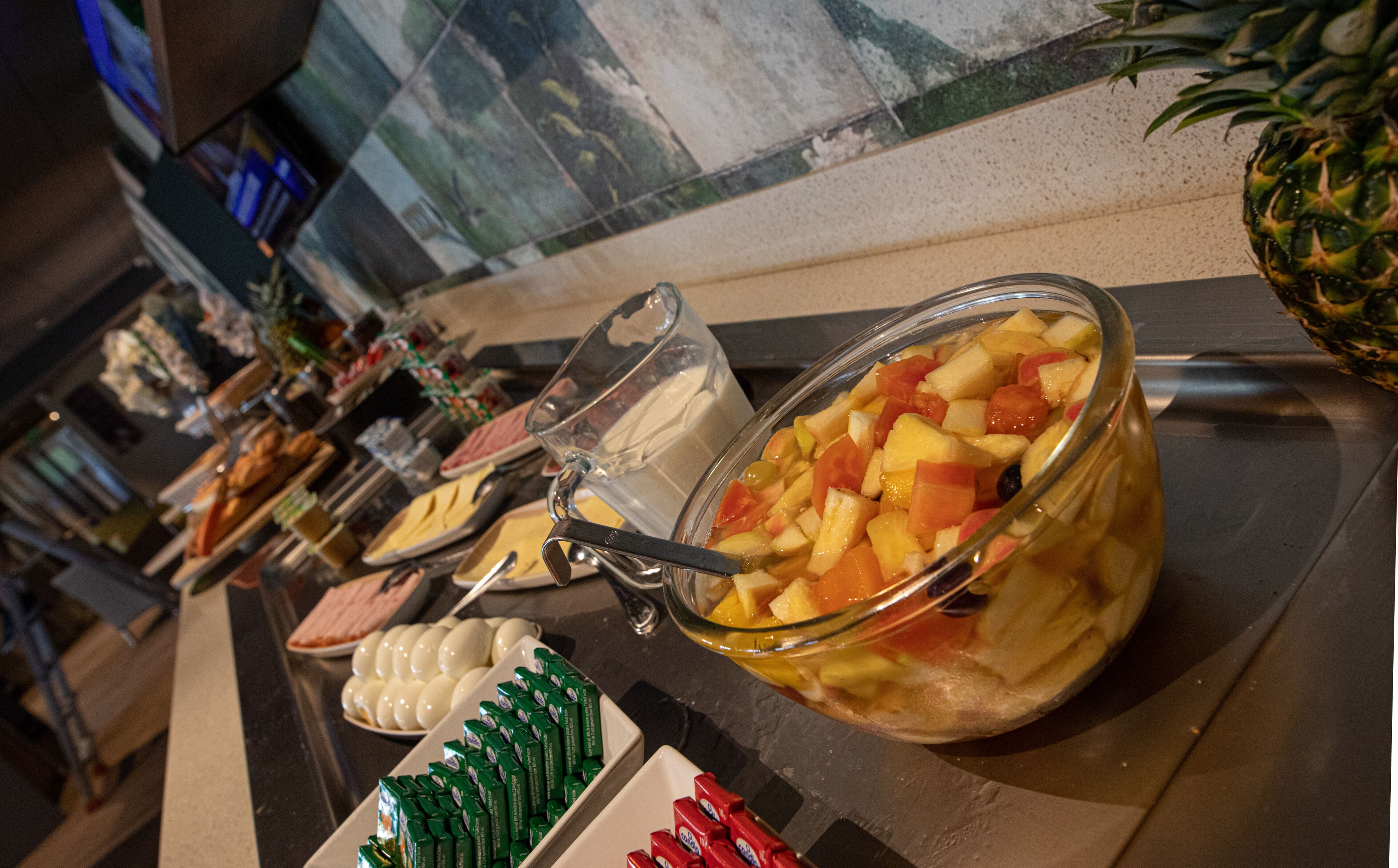 A buffet with a variety of food items including a fruit punch, eggs, and condiments.