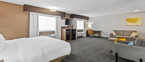 A hotel room with a bed, a sofa, a desk, and a TV.