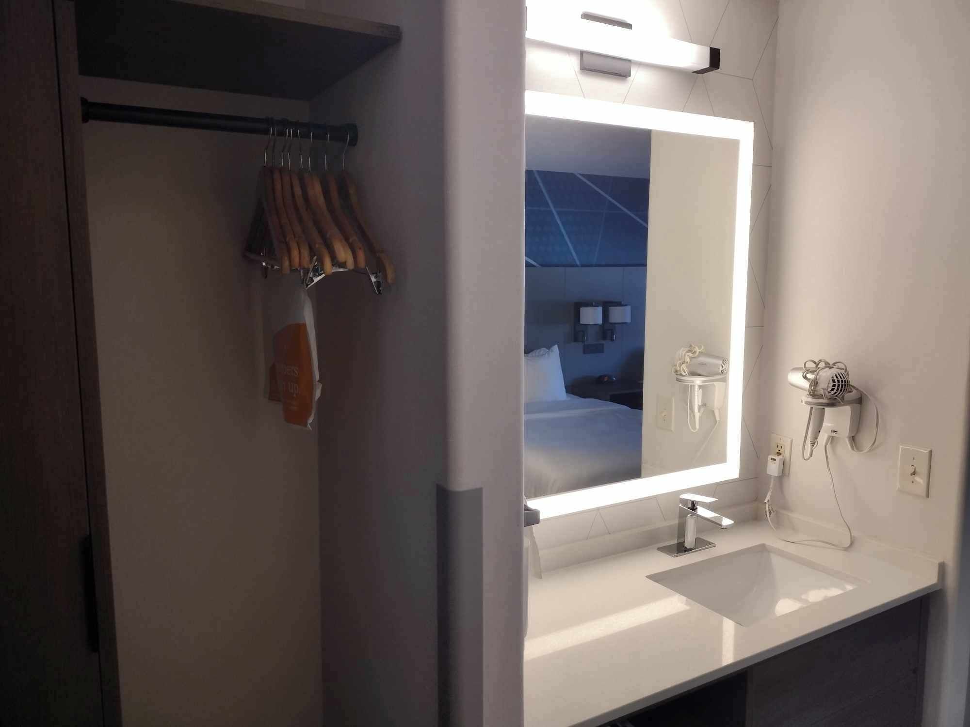 Un baño moderno con un espejo grande, un lavamanos y un secador de pelo montado en la pared.