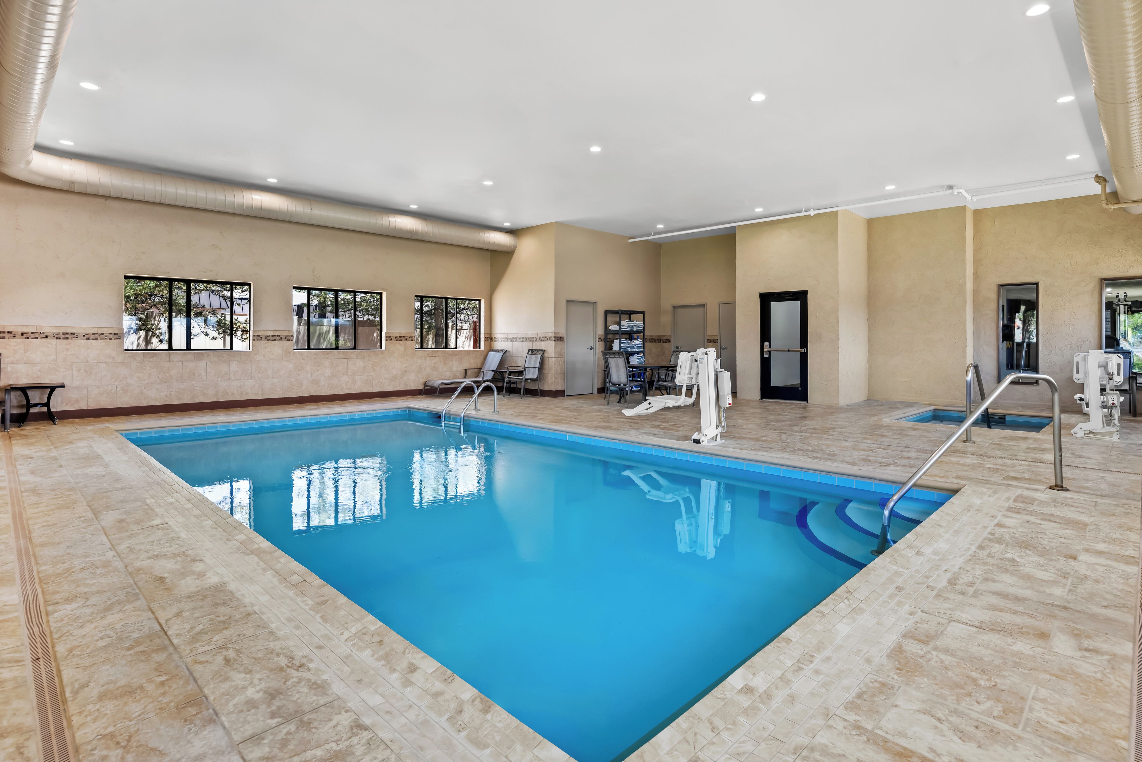 Ein Innenpool mit klarem Wasser, umgeben von gefliesten Wänden und einer Decke mit eingelassener Beleuchtung.