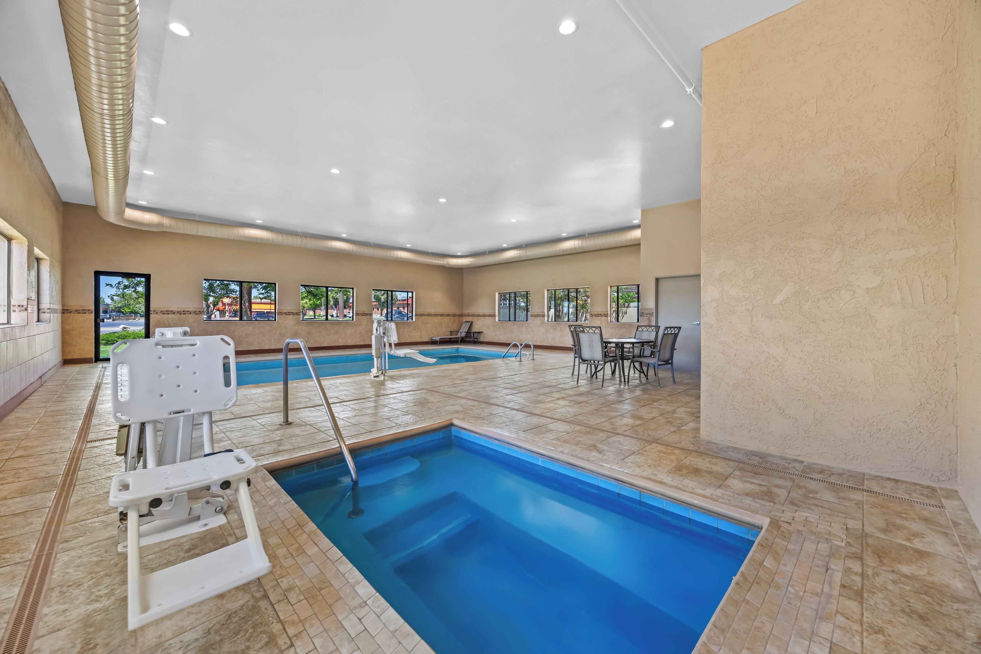 An indoor swimming pool with a clear view of the pool area, including the poolside chairs and the pool ladder.
