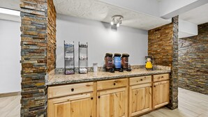 A kitchen with a granite countertop, wooden cabinets, and a stone accent wall. - Comfort Inn Grand Junction I-70 (Grand Junction)