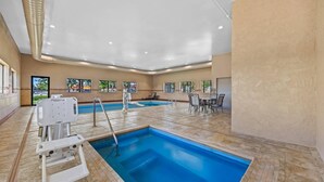 An indoor swimming pool with a lifeguard chair, pool ladder, and a seating area with tables and chairs. - Comfort Inn Grand Junction I-70 (Grand Junction)