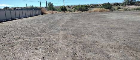 Uma área de estacionamento de cascalho com cerca e postes de eletricidade.