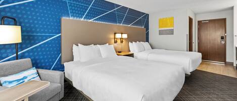 Una habitación de hotel con una cama grande, un sofá, un escritorio y una pared con diseño geométrico.