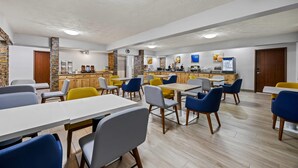 A spacious dining area with multiple tables and chairs, a kitchen in the background, and a modern ceiling design. - Comfort Inn Grand Junction I-70 (Grand Junction)