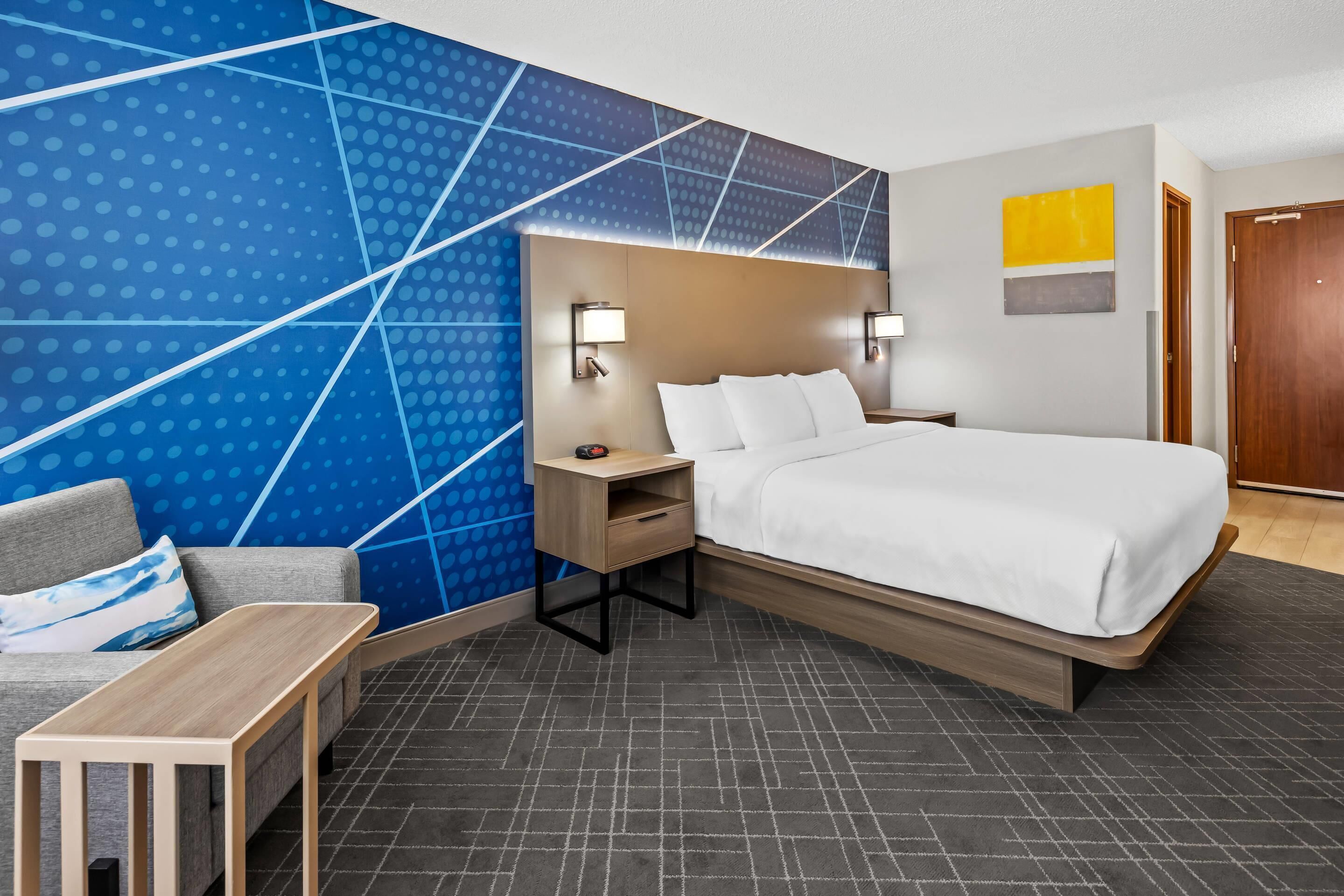 Camera d'albergo moderna con un letto grande, un comodino, una scrivania e un divano.