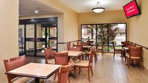 A restaurant with tables and chairs, a TV screen advertising free Wi-Fi, and a view of the outside. - Red Roof Inn & Suites Columbus - West Broad (Columbus)