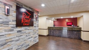 A Red Roof Inn reception area with a stone wall, a reception desk, and a sign indicating free Wi-Fi in all rooms. - Red Roof Inn & Suites Columbus - West Broad (Columbus)