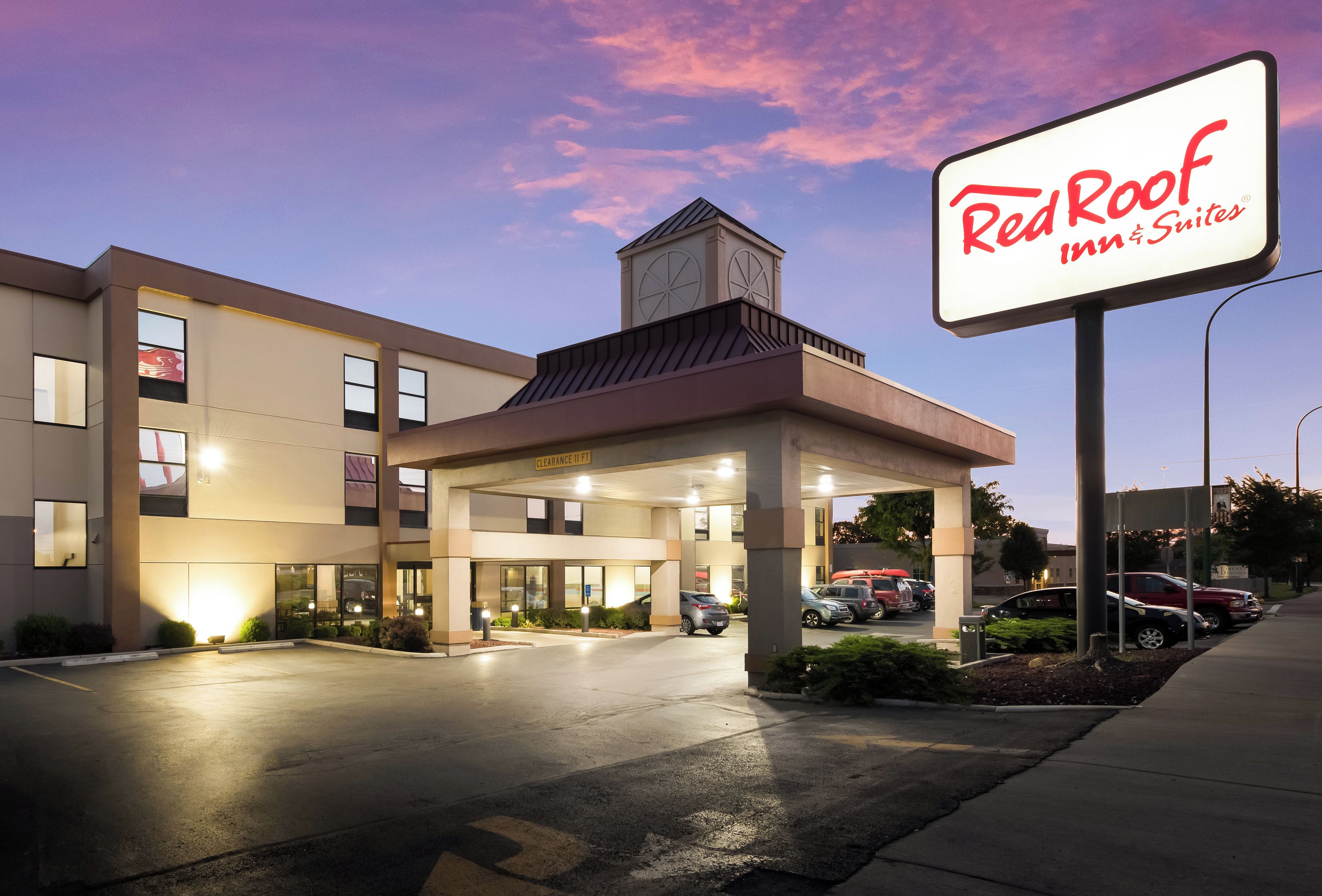 Edificio de Red Roof Inn & Suites con entrada cubierta, múltiples ventanas y estacionamiento.