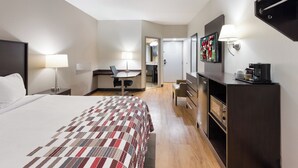 A hotel room with a large bed, a desk with a chair, a dresser, a television, and a coffee machine. - Red Roof Inn & Suites Columbus - West Broad (Columbus)