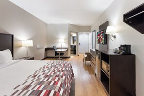 A hotel room with a large bed, a desk with a chair, a dresser, a television, and a coffee machine. - Red Roof Inn & Suites Columbus - West Broad (Columbus)