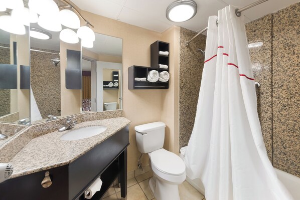 A bathroom with a sink, mirror, toilet, and shower curtain.