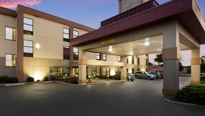 A hotel entrance with a covered parking area, a sign indicating a 11 ft clearance, and a clock tower. - Red Roof Inn & Suites Columbus - West Broad (Columbus)