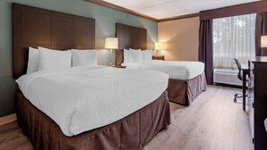 A hotel room with two beds, a desk, and a large window.