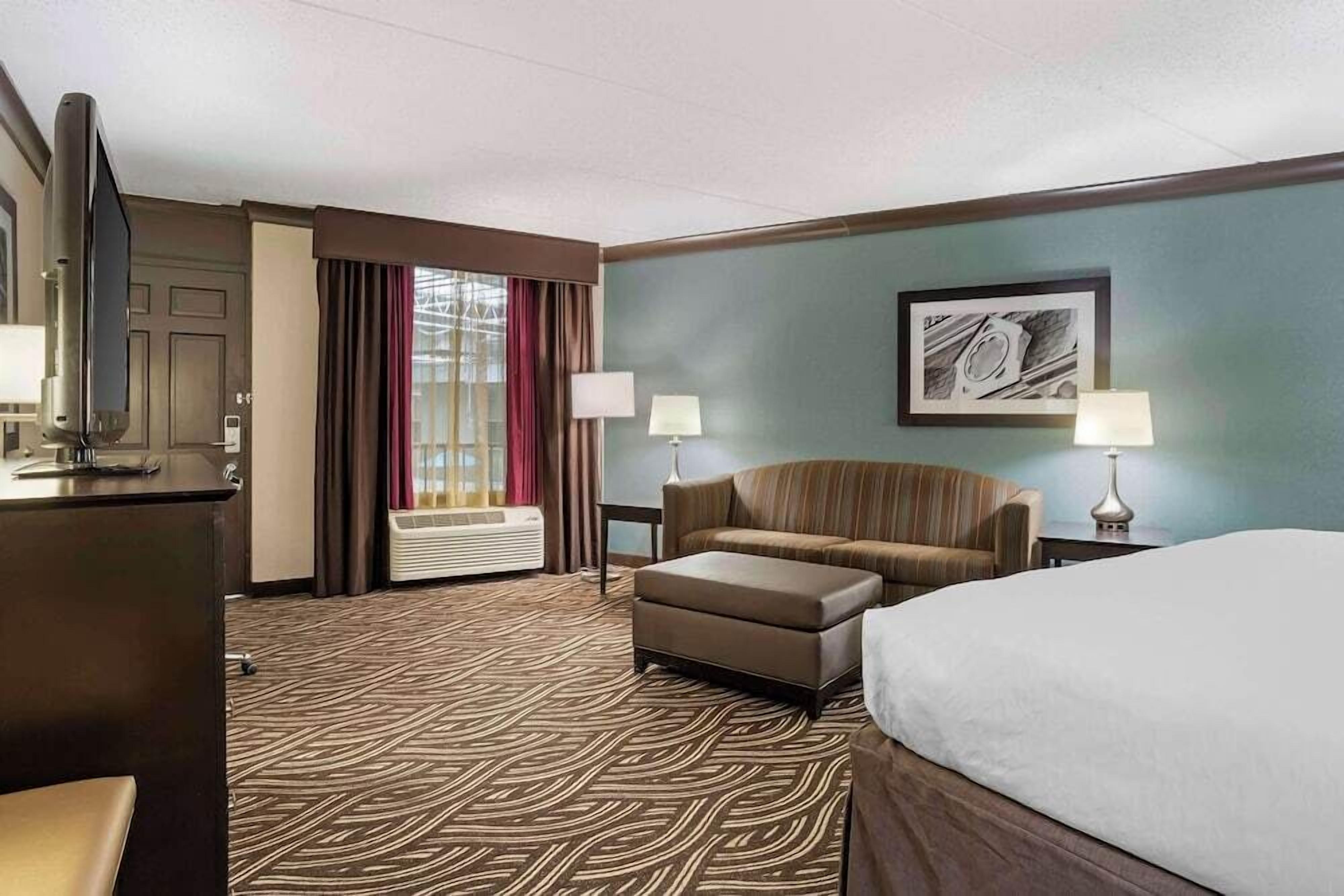 A hotel room with a bed, a sofa, a TV, and a desk.