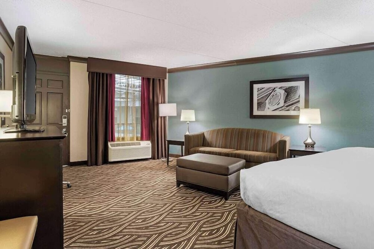 A hotel room with a bed, a sofa, a TV, and a desk.