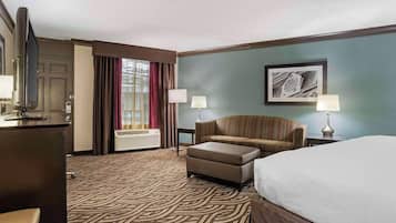 A hotel room with a bed, a sofa, a TV, and a desk.
