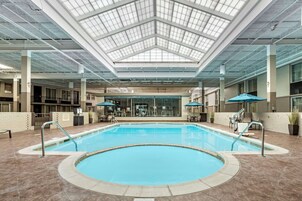 Una piscina con techo de vidrio, asientos interiores y pared de ladrillo.