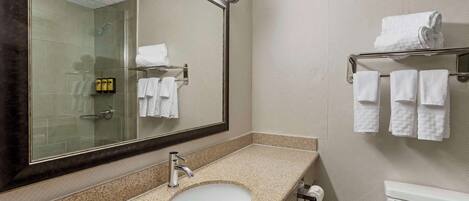 Un baño con lavamanos, espejo, toallero y retrete.