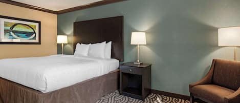 A hotel room with a bed, two bedside tables with lamps, a chair, and a patterned carpet.