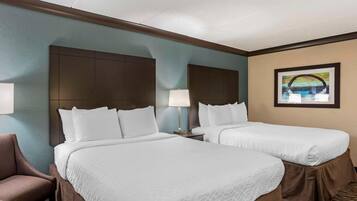 A hotel room with two beds, a headboard, a lamp, a chair, and a framed picture on the wall.