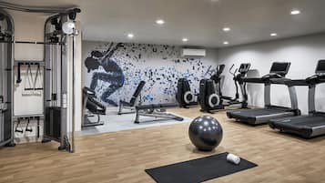 Un gimnasio con equipo de ejercicio, cintas de correr y una pared con una imagen pixelada.