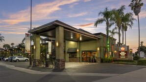 A hotel entrance with a covered outdoor area, palm trees, and a Best Western Plus sign.