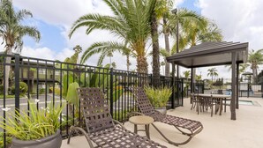 A rooftop patio with lounge chairs, a small table, and a pergola.